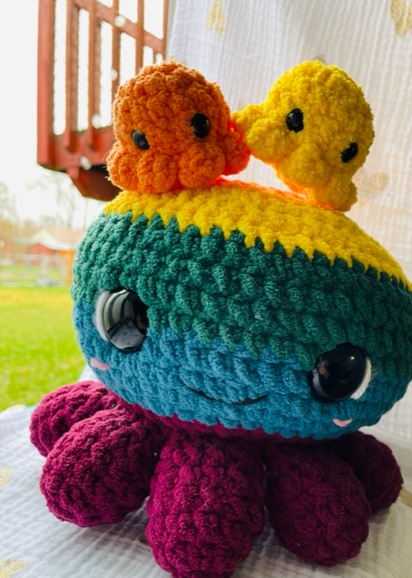 orange, yellow, green, blue, purple striped crochet octopus with 2 octopus babies on top